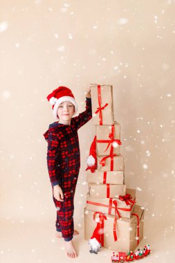 Noel şapkalı ve noel hediyeli küçük çocuk. Tebrik kartı. Kış tatili kavramı.