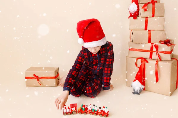 Malý chlapec s vánočním kloboukem a vánočními dárky. Pozdrav. Koncept zimních prázdnin. — Stock fotografie
