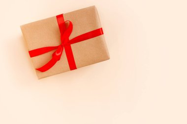 Bej arka planda kırmızı fiyonklu Noel hediyesi kutusu. Tatil konsepti, yeni yıl hediyeleri.