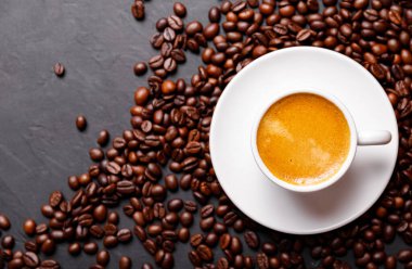 Sabah menüsü için süt köpüklü sıcak sade kahve beyaz seramik bardakta kahve çekirdekleri kavrulmuş.