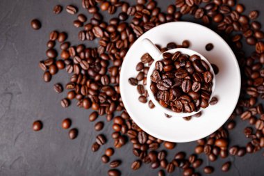 Sabah menüsü için süt köpüklü sıcak sade kahve beyaz seramik bardakta kahve çekirdekleri kavrulmuş.