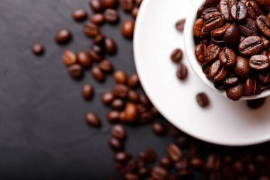 Sabah menüsü için süt köpüklü sıcak sade kahve beyaz seramik bardakta kahve çekirdekleri kavrulmuş.