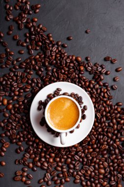 Sabah menüsü için süt köpüklü sıcak sade kahve beyaz seramik bardakta kahve çekirdekleri kavrulmuş.