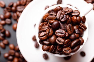 Sabah menüsü için süt köpüklü sıcak sade kahve beyaz seramik bardakta kahve çekirdekleri kavrulmuş.