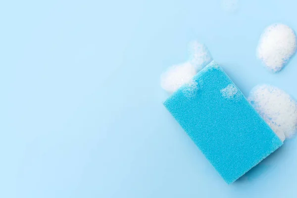 Multicolored sponges for cleaning on a blue background. Space for text