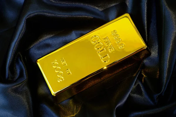 Pürüzsüz siyah ipek kumaş, lüks kumaş arka planda 1 kg altın külçe 