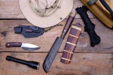 A knife with equipment for survival in the forest  on an old wooden floor