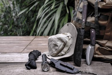 Eski ahşap bir zeminde, ormanda hayatta kalmak için gerekli aletlerle dolu bir bıçak.