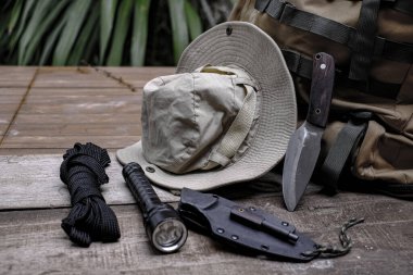 Eski ahşap bir zeminde, ormanda hayatta kalmak için gerekli aletlerle dolu bir bıçak.