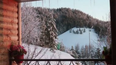 Ahşap balkon dağ ve orman manzaralı güzel bir kış manzarası sunar.