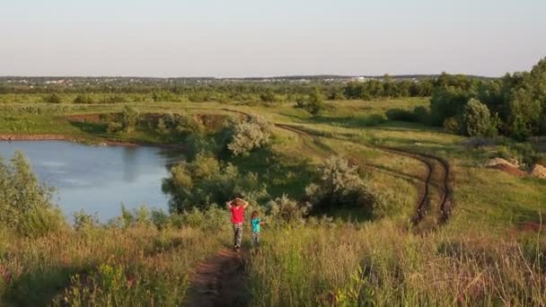 Rosja, Saratow - czerwiec 2020: dzieci spacerują po wiejskiej drodze w stepie nad jeziorem — Wideo stockowe