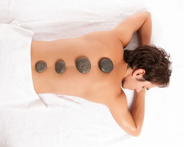 Junger Mann auf einem Wellnessbereich bekommt eine Hot-Stone-Massage. Stockfoto