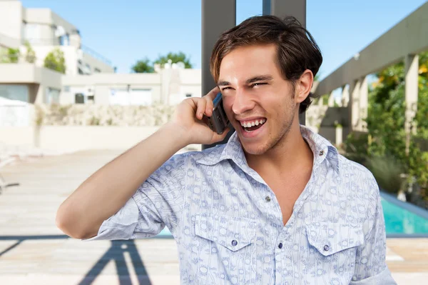 Jonge mannelijke volwassene op de mobiele telefoon lachen. Stockafbeelding