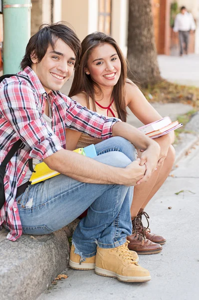 Jonge studenten zitten in de straat houdt van boeken. — Stockfoto