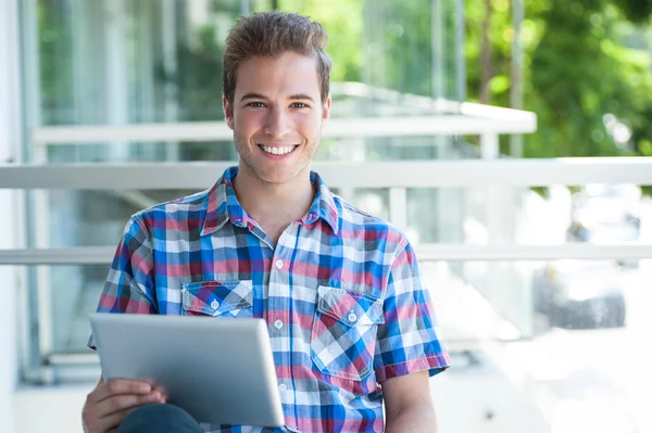 Young smiley male using tablet pc looking at the camera — Stock Photo, Image
