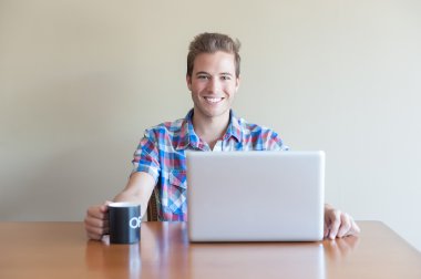 jonge volwassene met behulp van computer en bedrijf kopje koffie