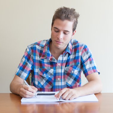 bir kalem ve bir kitap okuyan genç yetişkin