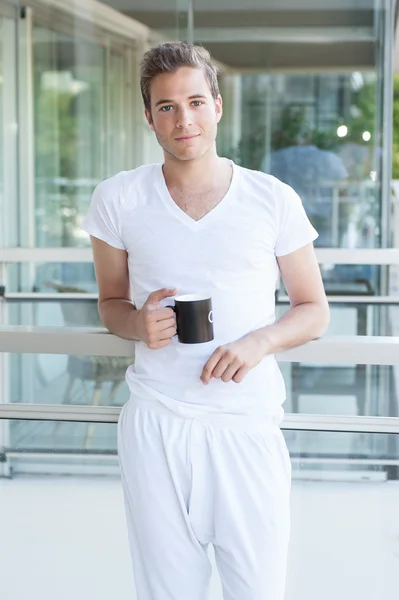 Adulto jovem segurando uma xícara de café — Fotografia de Stock