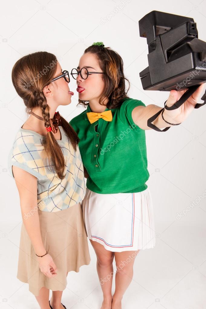 Young nerdy girls taking a selfie with instant camera.