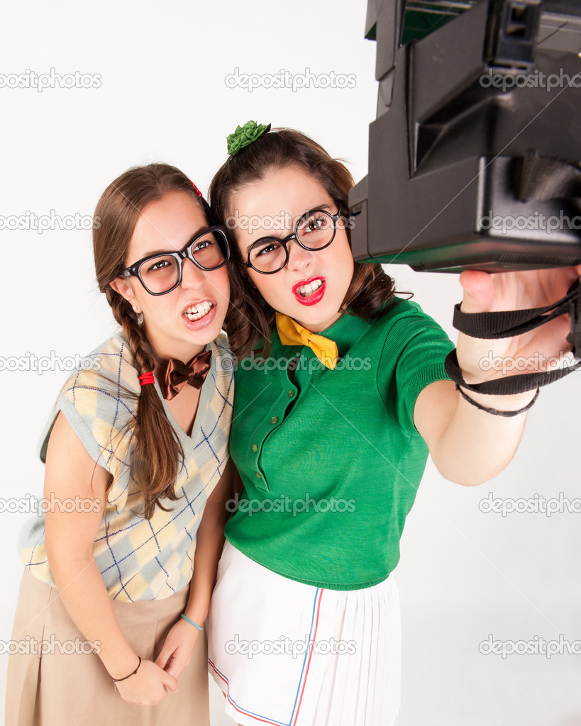 Young nerdy girls taking a selfie with instant camera.