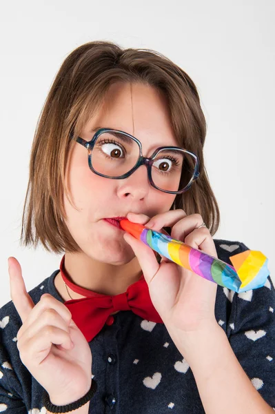 Niedliche nerdy Mädchen bläst ein Party-Horn. — Stockfoto