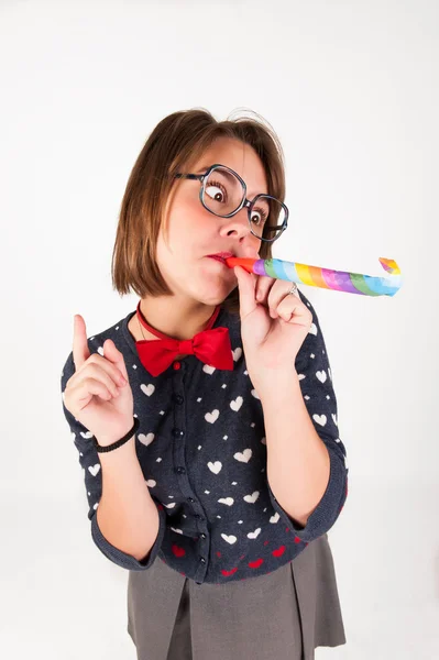 Menina nerd bonito soprando um chifre de festa . — Fotografia de Stock