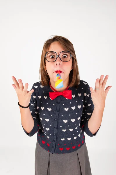 Cute nerdy girl blowing  a party horn. — Stock Photo, Image