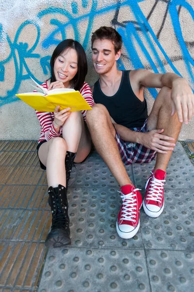 Joven pareja multiétnica leyendo un libro . — Foto de Stock