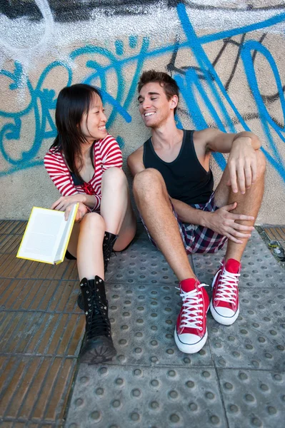 Молодая многонациональная пара, читающая книгу . Лицензионные Стоковые Фото