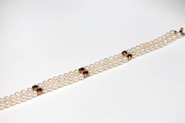 Doğal incilerden yapılmış bir bilezik, altın tokalı taştan ve elmaslardan. Sarı altın ve değerli taşlar