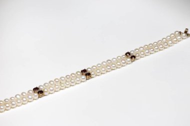 Doğal incilerden yapılmış bir bilezik, altın tokalı taştan ve elmaslardan. Sarı altın ve değerli taşlar