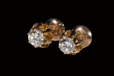 Siyah arkaplanda doğal elmaslar olan altın küpeler. Klasik düğün çiçeği şekilli çerçeve ve vida kilidi.