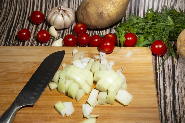 Čerstvě nakrájená cibule na dřevěné sekací desce vedle zeleniny — Stock fotografie