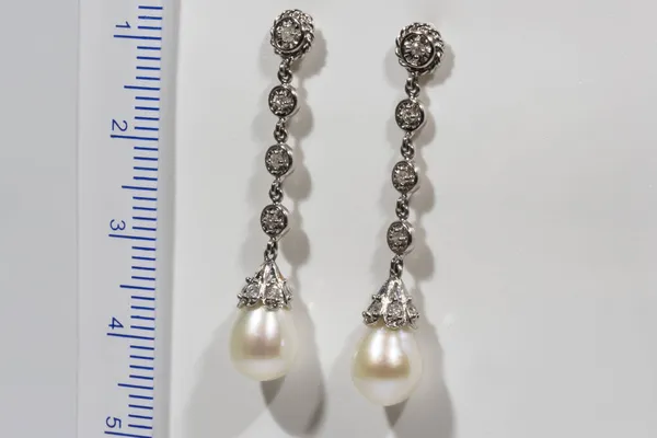 Longo designer brinco de ouro com pérolas e diamantes em um fundo branco ao lado da régua — Fotografia de Stock