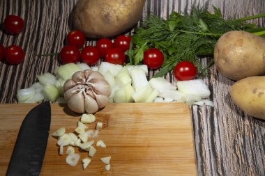 Ahşap zemin üzerinde ince doğranmış sarımsak. Saf ahşap bir mutfak doğrama tahtasının üzerinde sağlıklı organik, mor, sarımsaklı süper yiyecek kavramı. Ezilmiş yemek ve sarımsak kokusu için.