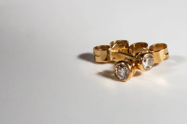 Boucles d'oreilles en or jaune avec de vrais diamants. Petites boucles d'oreilles décontractées avec diamants simples. Belles boucles d'oreilles sur fond blanc. — Photo
