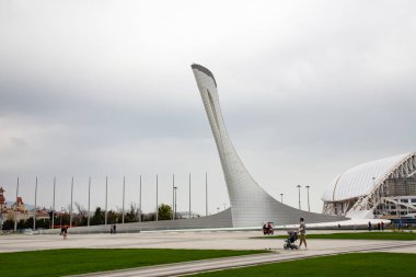 Adler, Sochia - 11 Nisan 2021: Soçi 'deki Büyük Olimpiyat Meşalesi, ülkenin bayrakları ve Buzdağı Sarayı' nın bayraklarıyla dağların arka planına karşı.