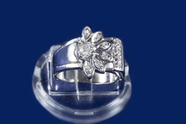 Anello in oro bianco con diamanti naturali, una cornice come un fiore, su sfondo blu — Foto Stock