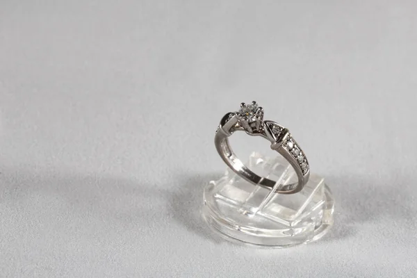 White gold ring with natural diamonds on a jewelry stand on a gray background — Stock Photo, Image