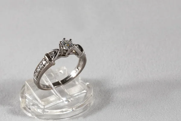 Anel de ouro branco com diamantes naturais em um suporte de jóias em um fundo cinza — Fotografia de Stock