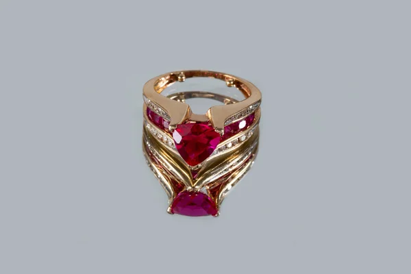 Gyönyörű sárga arany gyűrű rubinnal és gyémántokkal egy szürke tükör háttér közelkép — Stock Fotó