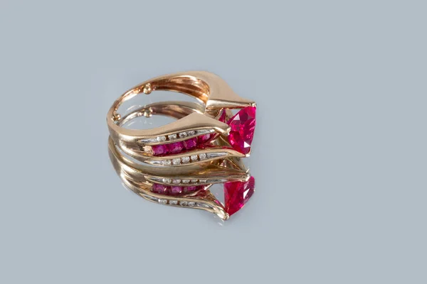 Gyönyörű sárga arany gyűrű rubinnal és gyémántokkal egy szürke tükör háttér közelkép — Stock Fotó
