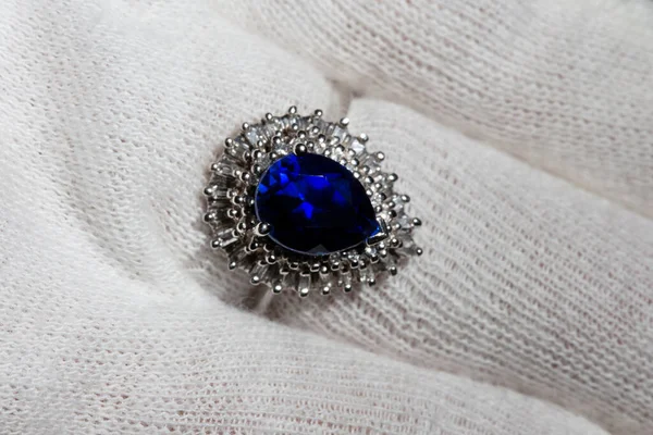 Λευκό χρυσό δαχτυλίδι κοσμήματα σε κοντινό πλάνο με ένα μεγάλο μπλε αχλάδι-cut ζαφείρι και διαμάντια στο ποτάμι σε ένα λευκό γάντι — Φωτογραφία Αρχείου