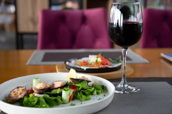 Gastronomische keuken in het visrestaurant: mosselen en een glas rode wijn op een houten tafel. Rechtenvrije Stockfoto's