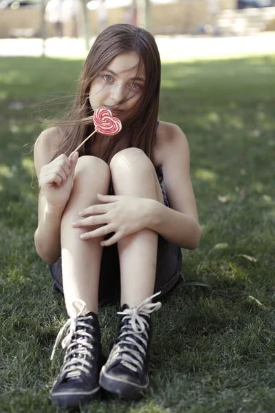 çimenlerin üzerinde lolipop yiyen kız
