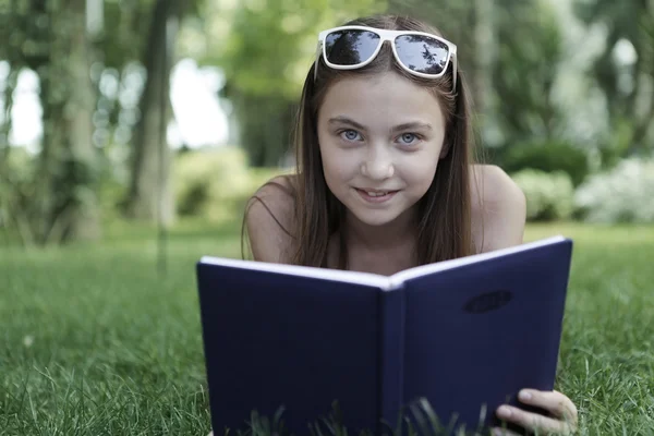 Flicka med boken på gräs Stockbild