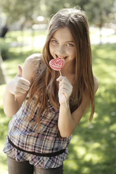 Chica feliz comiendo piruleta Imágenes de stock libres de derechos