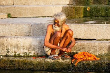 Varanasi, India - april 18 and 19, 2018: People doing spiritual ceremonies, washing and bathing on the ghats of the holy river Ganges in Varanasi in India clipart