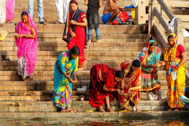 Varanasi, Hindistan - 18 ve 19 Nisan 2018: İnsanlar Hindistan 'ın Varanasi kentindeki Ganj nehrinin ghatlarında ruhani törenler yapıyor, yıkanıyor ve yıkanıyor.