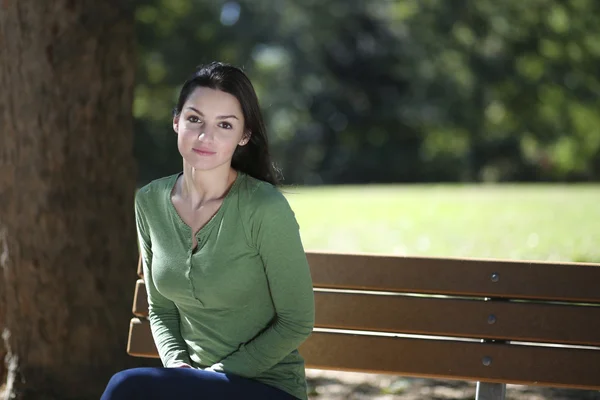 Junge Frau sitzt im Park — Stockfoto